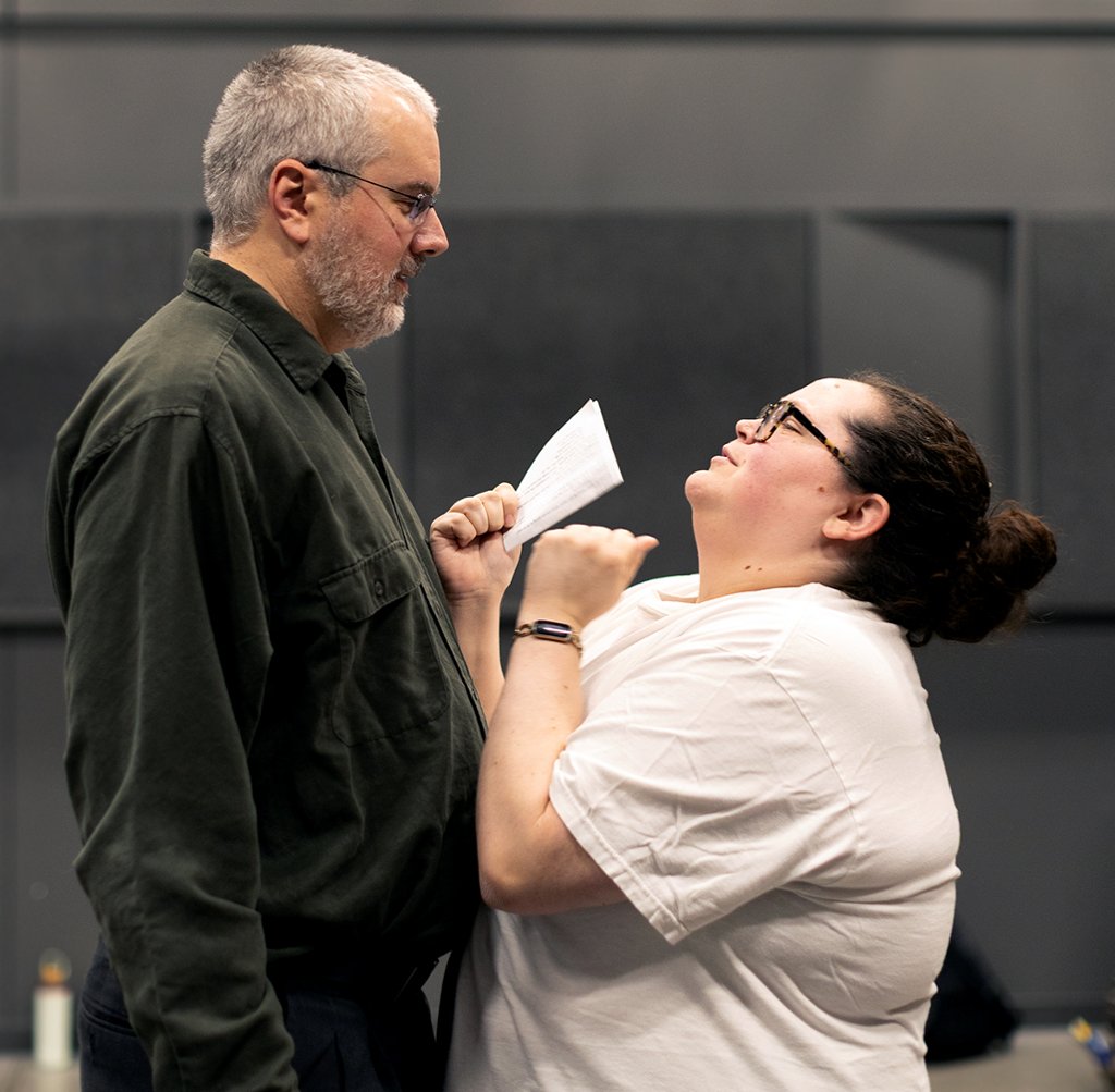 two actors facing each other and acting in a scene during rehearsal